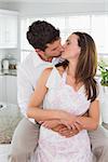 Loving young couple kissing in the kitchen at home