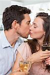 Close-up of a loving young couple with wine glasses kissing at home