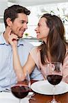 Loving young couple with wine glasses at dining table