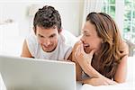 Happy young couple using laptop in bed at home