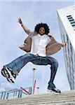 Portrait of young man outdoors, jumping down staircase, looking at camera and smiling, Mannheim, Germany