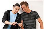 Two young men, friends looking at cell phone together, studio shot on white background