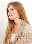 Close-up portrait of young, blond, long-haired woman lying on stomach, looking at camera and smiling, studio shot on white background