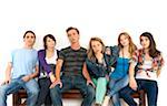 Portrait of six young people sitting together on a bench, studio shot on white background