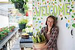 Summer on an organic farm. A girl holding a basket of fresh corn standing by the Welcome sign.