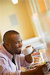 A man in a cafe holding a cup of coffee.