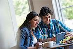 A couple seated looking at a digital tablet.