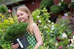 An organic flower plant nursery. A young girl carrying a plant in a pot.
