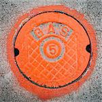 A gas manhole cover, round and painted orange on the road in Seattle.