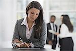 Young professionals at work. A woman in a grey jacket, using a digital tablet.