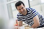 An office or apartment interior in New York City. A man in a striped tee shirt leaning on the breakfast bar.