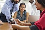 Business people gathered in an office in the city. A team of four people, men and women, gathering around a laptop.