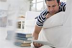 Business people. The office in summer. A man lying on his front on a sofa, in a quiet airy office environment. Using a digital tablet.