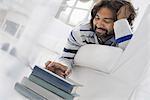 Business people. The office in summer. A man lying on his stomach on a sofa, in a quiet airy office environment using a smart phone.