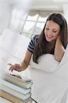 Business people. The office in summer. A woman lying on her front on a sofa, in a quiet airy office environment using a smart phone.