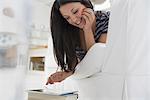 Business people. The office in summer. A woman lying on her front on a sofa, in a quiet airy office environment using a smart phone.