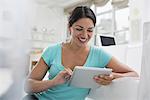 Business people. The office in summer. A young woman sitting comfortably in a quiet airy office environment. Using a digital tablet.