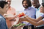 An open plan office in New York City. A working lunch, a salad buffet. A group of men and women of mixed ages and ethnicities meeting together.