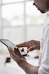 Professionals in the office. A light and airy place of work. A man in a white shirt using a digital tablet.