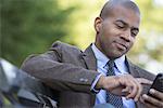 Business people in the city. Keeping in touch on the move. A man seated on a bench. Checking his cell phone.