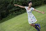 A young woman in a summer dress with her arms outstretched, celebrating freedom.