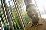 A man smiling at the camera under the shade of trees in summer.