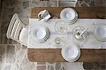 An overhead view of a table laid with white crockery and glassware.