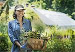 A young woman holding a large box of freshly cut vegetables.