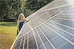 A young girl standing beside and leaning against a large solar panel installation.