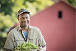 A man holding a bowl of fresh salad leaf cuttings.