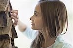 A child examining a bug box on a porch.