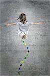 View from overhead of a child creating and walking along a line of coloured leaf shapes.