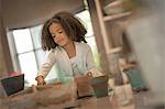 A young girl planting out seeds in clay pots.