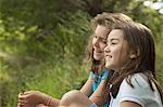 Two children, girls sitting side by side, laughing in the fresh air.