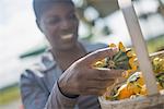 A woman with a basket of squash plants at a farm vegetable stand.