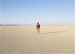 Man walking across a flat desert landscape