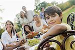 A family and friends having a meal outdoors.  A picnic or buffet in the early evening.