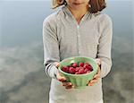 Nine year old girl holding bowl of organic raspberries