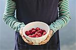 Nine year old girl holding bowl of organic raspberries