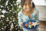 A young girl holding a plate of organic decorated Christmas cookies