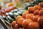 A farm stand display of fresh produce. Tomatoes and cucumbers.