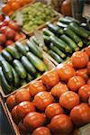 A farm stand display of organic vegetables. Produce. tomatoes and cucumbers.