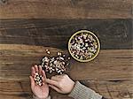 A person sorting different kinds of beans and pulses in her hands on a wooden table top.