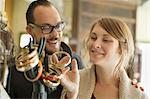 Two people, a man and woman looking at the objects displayed on a mannequin hand, antique jewellery and objects.