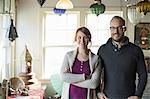 Two people standing in a store full of antique objects, a couple running a business.