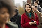 City life. A group of people on the go, keeping in contact, using mobile phones, and talking to each other. Two women and two men.