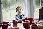 A child sitting at a table in a family home. A table laid for a meal.