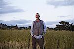 A man standing by a field of growing cereal crop, at the social care and work project, the Homeless Garden Project in Santa Cruz.