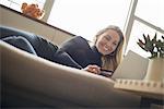 Woman at home, on-line shopping on sofa