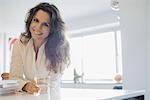 Woman at home in kitchen with glass of water